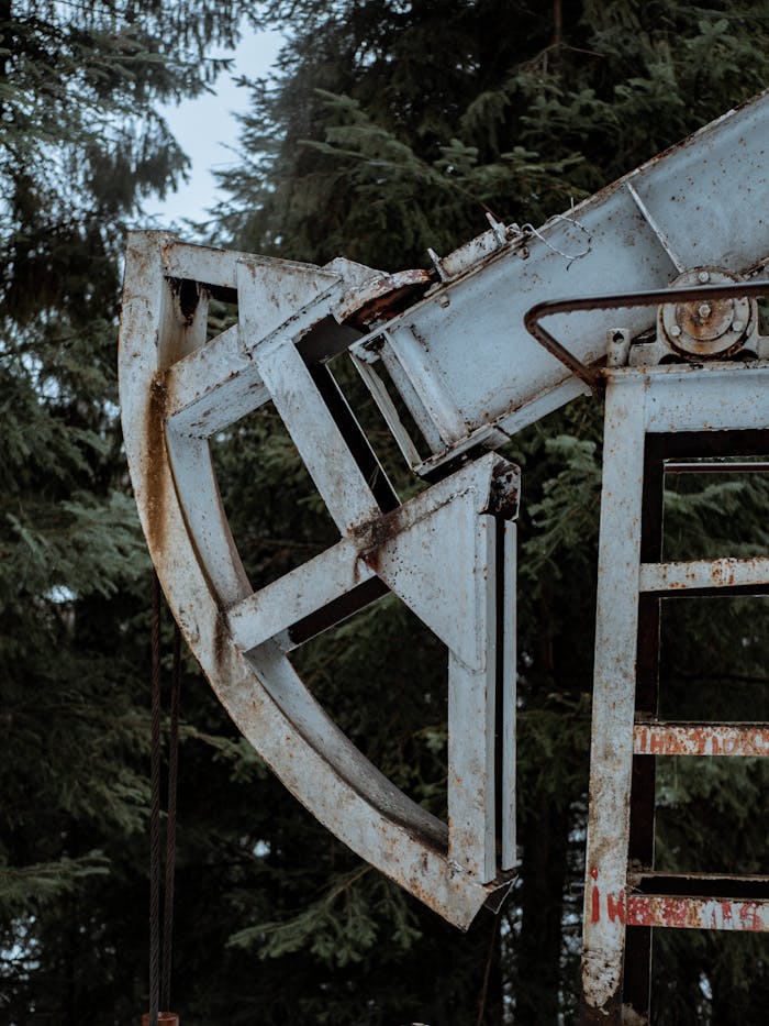 Mastering the First Impression: Your intriguing post title goes here Close-up of a rusted pumpjack amidst evergreen trees, symbolizing industry and nature.