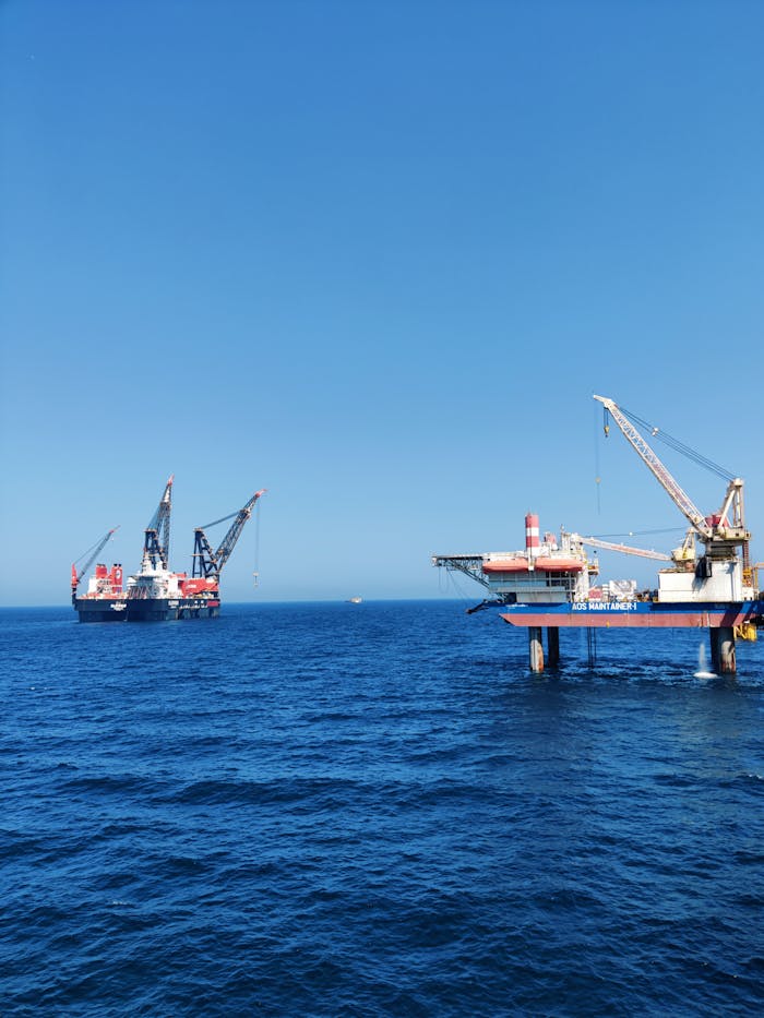 creative-03 Offshore oil platforms with cranes operating in the Persian Gulf under a clear blue sky.