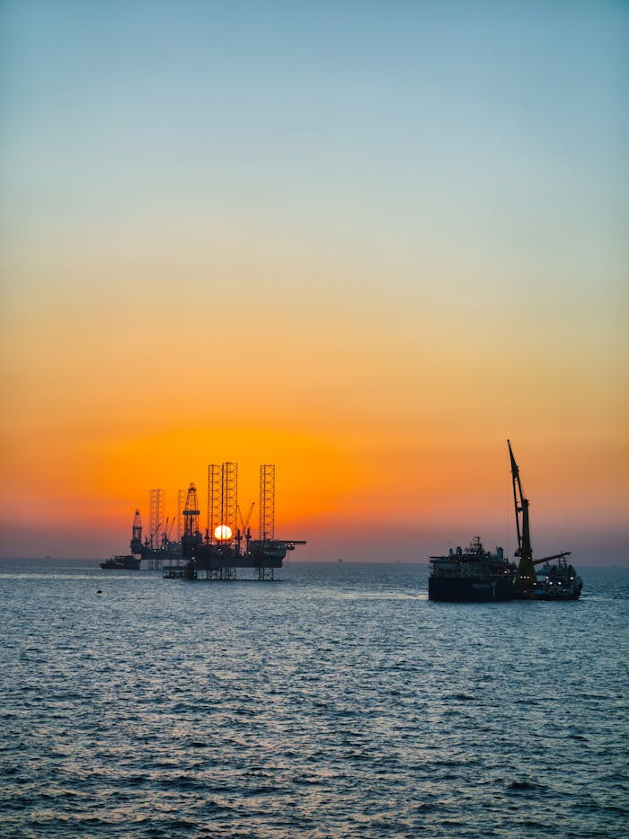 creative-02 A serene view of an offshore drilling rig and ship at sunset over the ocean.