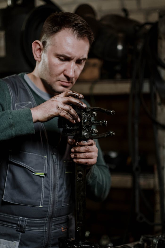digital Mechanic concentrating on repairing a car component in a dimly lit workshop.